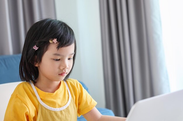 Kleine Aziatische studente studeert online met een laptop thuis