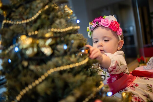 Kleine baby in de buurt van kerstboom voor nieuwjaarsfeest