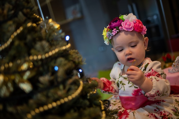 Kleine baby in de buurt van kerstboom voor nieuwjaarsfeest