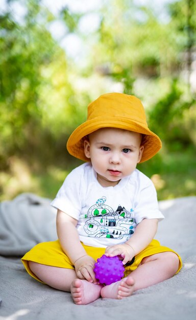 Kleine baby jongen zittend op een deken in het park op zoek naar camera close-up Baby jongen verkennen van de natuur