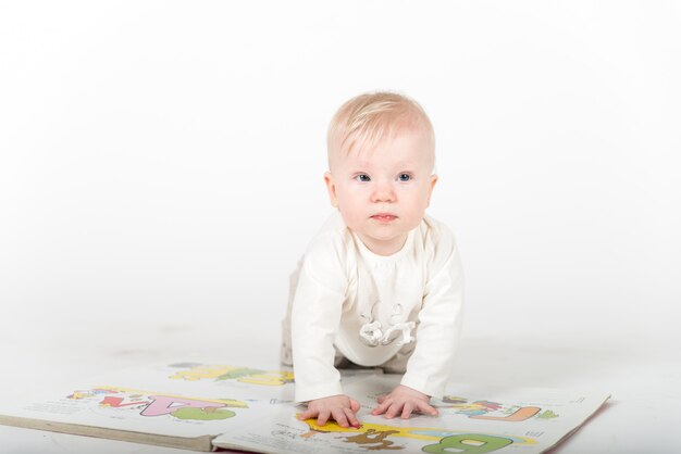 Kleine baby met het boek op het wit