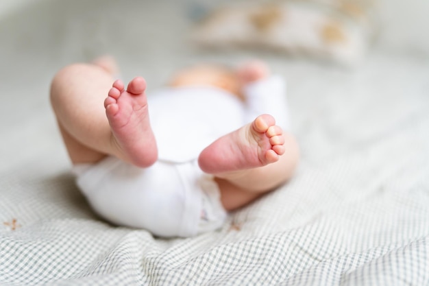 Kleine babybenen close-up Pasgeboren dragen lichaam liggend op bed eerste dagen thuis na geboorte babyverzorgingsconcept