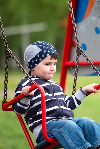 Kleine babyjongen die op een schommel rijdt