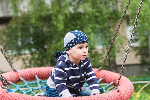 Kleine babyjongen die op een schommel rijdt