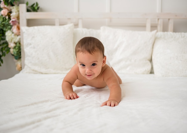 Kleine babyjongen kruipen op een wit bed