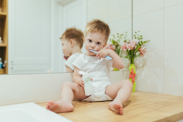 Kleine babyjongen leert zijn tanden poetsen in de badkamer