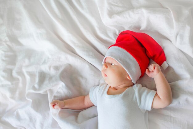 Kleine babyjongen liggend op wit linnen in de kerstmuts