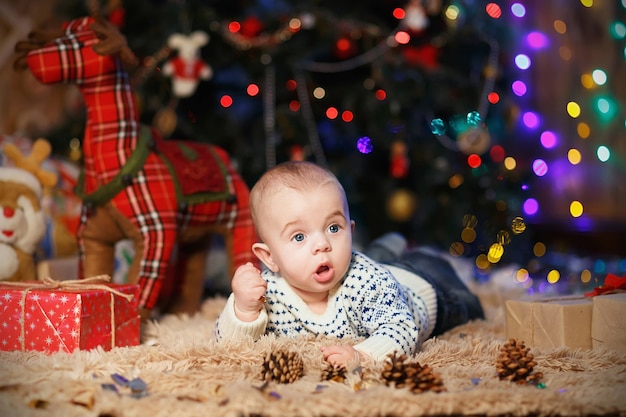 Kleine babyjongen liggend op zijn buik in de kamer met kerstversiering