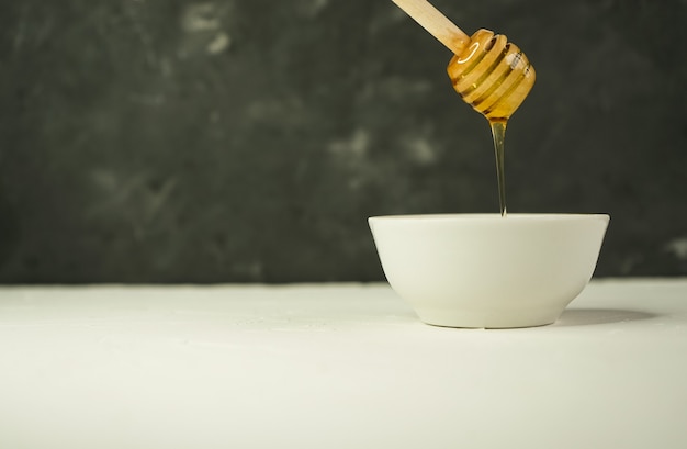 Kleine beker met natuurlijke honing en lepel