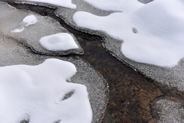 Kleine bevroren rivier met verse sneeuw op de rotsen in de winter