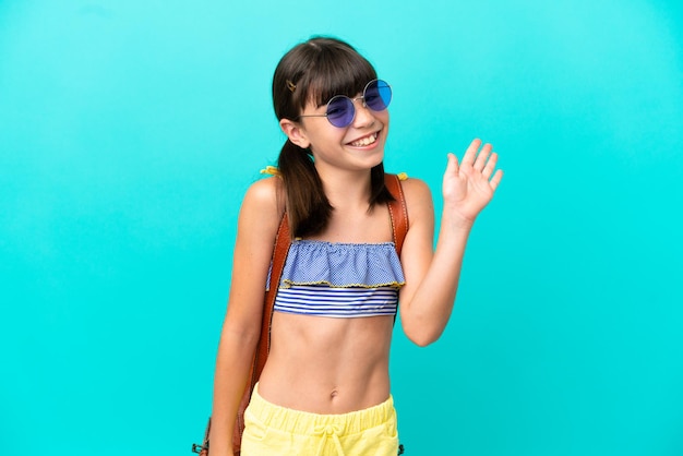 Kleine blanke jongen die naar het strand gaat geïsoleerd op blauwe achtergrond saluerend met de hand met gelukkige uitdrukking