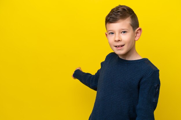 Kleine blanke jongen geïsoleerd op een gele achtergrond die zijn handen naar de zijkant uitstrekt om uit te nodigen om te komen