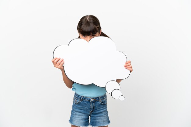 Kleine blanke jongen geïsoleerd op een witte achtergrond die een denkende tekstballon vasthoudt en erachter verstopt