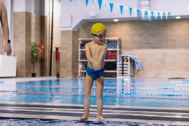 Kleine blanke jongen met een bril die in het zwembad gaat duiken. Hoge kwaliteit foto