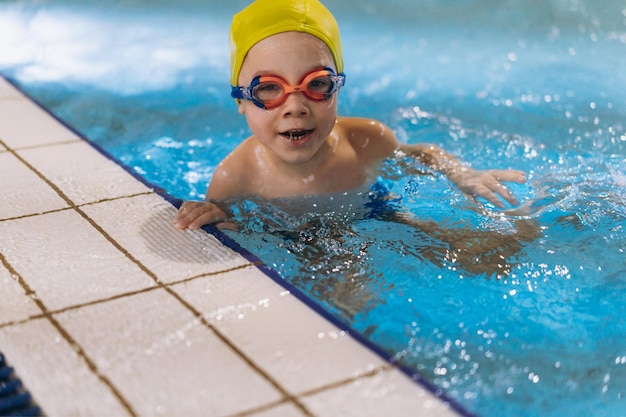 Kleine blanke jongen met een bril die uitkijkt vanuit het zwembad. Hoge kwaliteit foto met selectieve focus