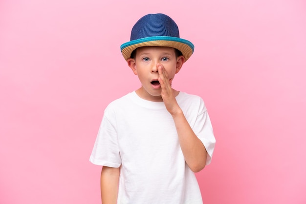 Kleine blanke jongen met een hoed op een roze achtergrond die met wijd open mond schreeuwt