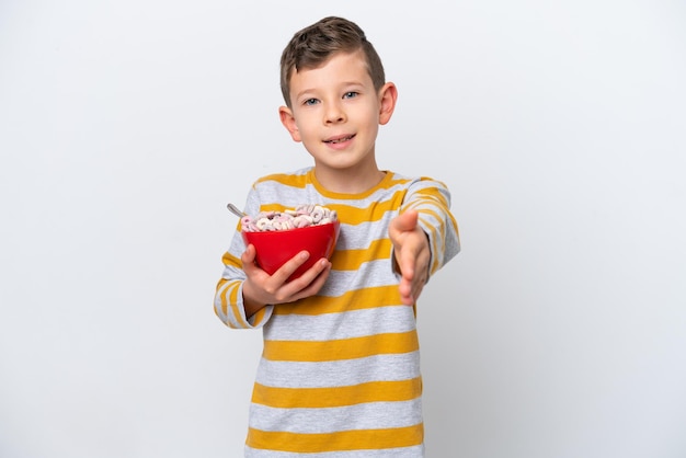 Kleine blanke jongen met een kom met granen geïsoleerd op een witte achtergrond handen schudden voor het sluiten van een goede deal