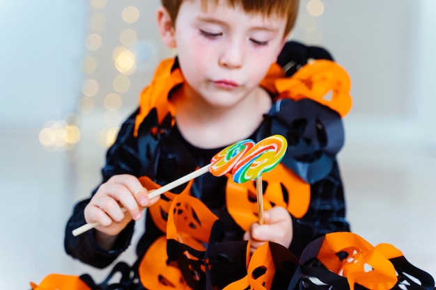 Kleine blanke jongen speelt met trick or treat snoep verzameld op Halloweens kostuumfeest