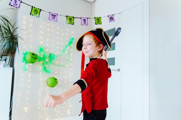 Kleine blanke jongen spelen met Halloween piraat kostuum thuis