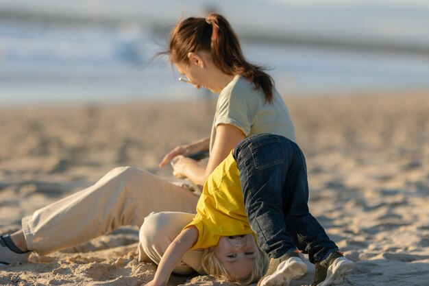 Kleine blonde jongen en zijn moeder hebben plezier op het strand