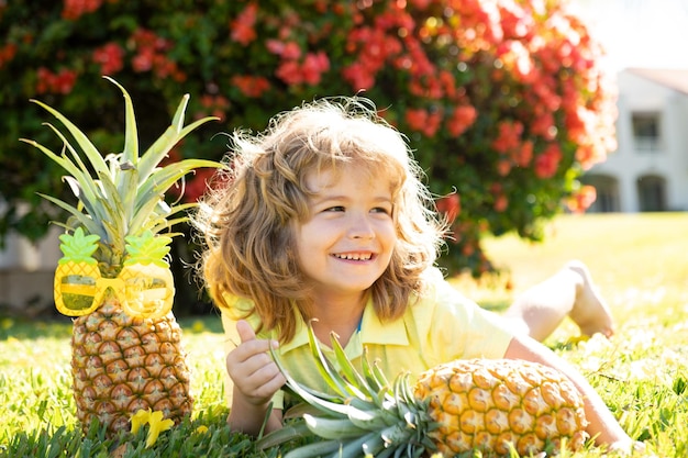 Kleine blonde jongen knuffelen ananas op natuur achtergrond jeugd gezonde voeding reclame clo