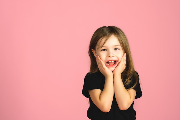 Kleine blonde meid is zeer verrast en kijkt naar de camera in de studio