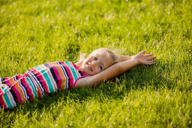 kleine blonde meisje liggend op het groene gras glimlachen