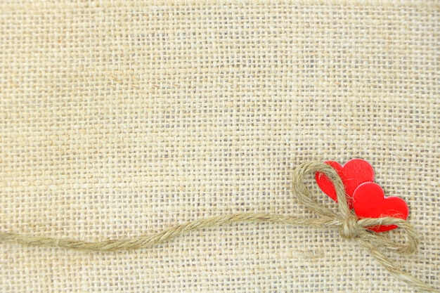Foto kleine boog touw zak met paar rood hart papier op bruine zak achtergrond