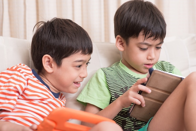 Foto kleine broers en zussen jongens spelen spel op tablet