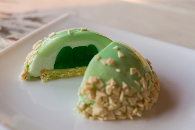 Kleine cake met groene vulling. Geglazuurd dessert met decoratie. Zachte biscuit en gelei. Smaak van munt.