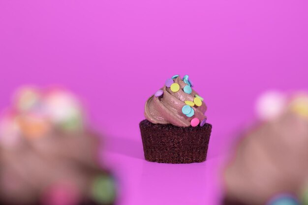 Foto kleine chocolade cupcake met een roze achtergrond en kleurrijke hagelslag