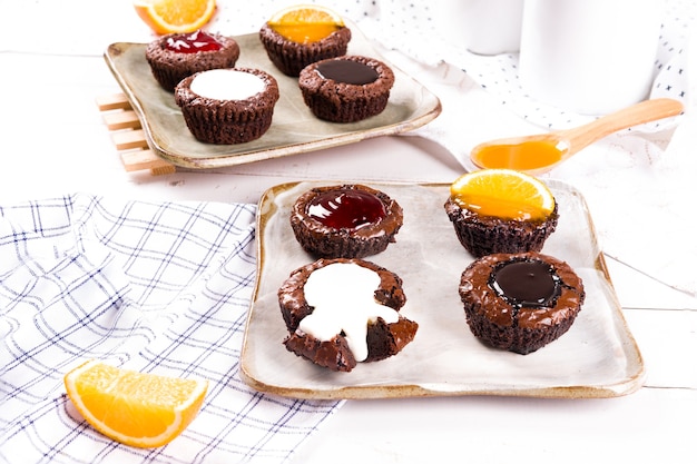 Kleine chocoladetaartjes met melk, aardbei, chocolade en sinaasappelsaus op witte houten tafel achtergrond.