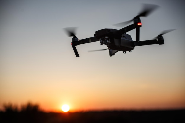 Kleine compacte quadcopter vliegt in de lucht op zonsondergang drone zweeft en blijft stabiel