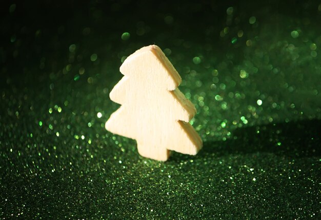 Kleine decoratieve houten kerstboom op sprankelende glitterachtergrond