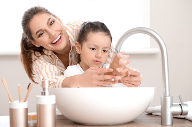 Kleine dochter met haar moeder handen wassen in de badkamer