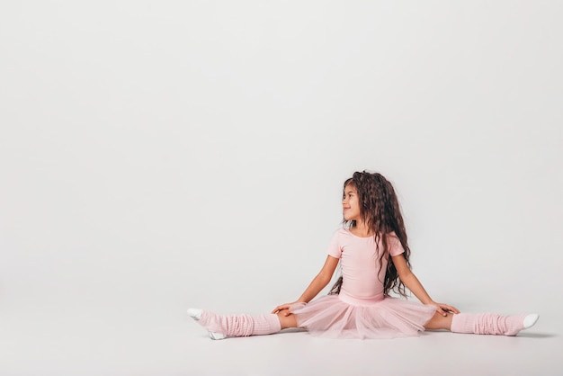 Foto kleine donkere ballerina danseres in een roze tutu academie student poseren op witte achtergrond