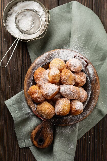 Kleine Donuts. Zelfgemaakte wrongel gebakken koekjes in diep vet en bestrooid met poedersuiker in een vintage bord