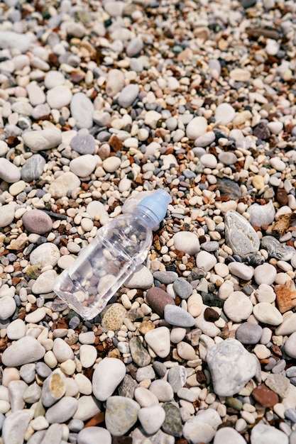 Kleine fles water ligt van bovenaf op een kiezelstrand uitzicht