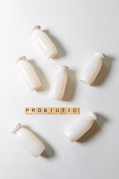 Kleine flesjes met probiotica en prebiotica zuiveldrank op witte achtergrond. Productie met biologisch actieve toevoegingen. Fermentatie en dieet gezond voedsel. Bio yoghurt met nuttige micro-organismen.
