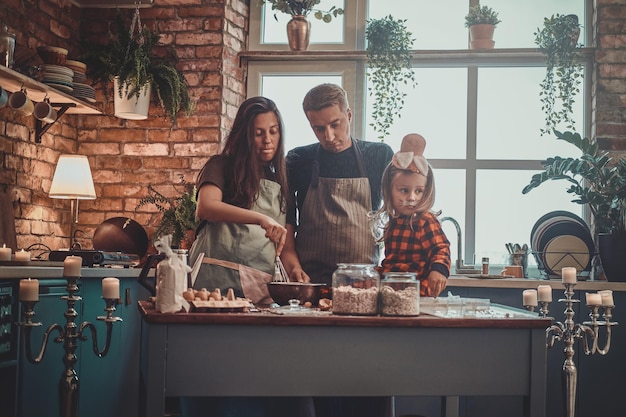 Kleine gelukkige familie kookt samen iets lekkers voor halloween-feest.