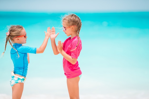 Kleine gelukkige grappige meisjes hebben veel plezier op tropisch strand samen spelen.