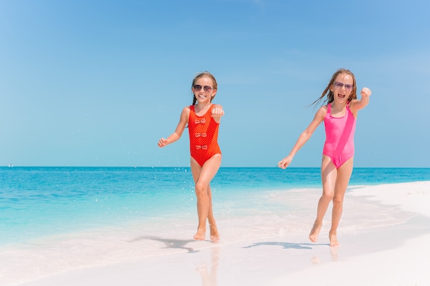 Kleine gelukkige grappige meisjes hebben veel plezier op tropisch strand samen spelen.