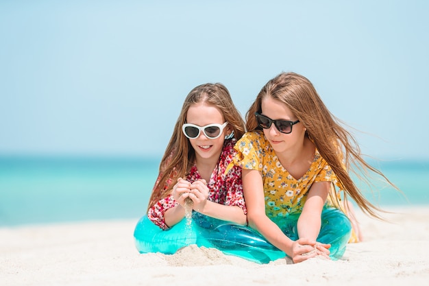 Kleine gelukkige grappige meisjes hebben veel plezier op tropisch strand samen spelen.