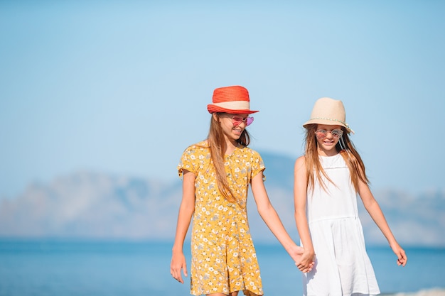 Kleine gelukkige grappige meisjes hebben veel plezier op tropisch strand samen spelen.