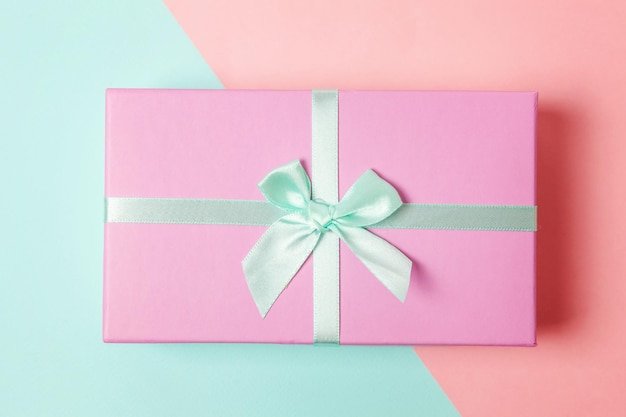 Kleine geschenkdoos verpakt roze papier geïsoleerd op blauw en roze pastel kleurrijke trendy geometrische achtergrond Kerstmis Nieuwjaar verjaardag Valentijn viering aanwezig romantisch concept