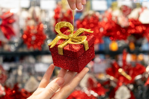 Kleine glanzende rode geschenkdoos met gouden lint in handen van vrouwen. cadeau voor speciale datum, verjaardag, jubileum of bruiloft. tweede kerstdag of valentijnsdag als symbool van liefde en genegenheid.