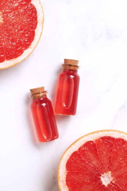 Kleine glazen flacon met aroma-essentiële olie met grapefruit vers plakje Plat bovenaanzicht gezichtsserum in fles op marmeren tafel SPA ontspannen gezicht huidverzorging en lichaamsbehandeling