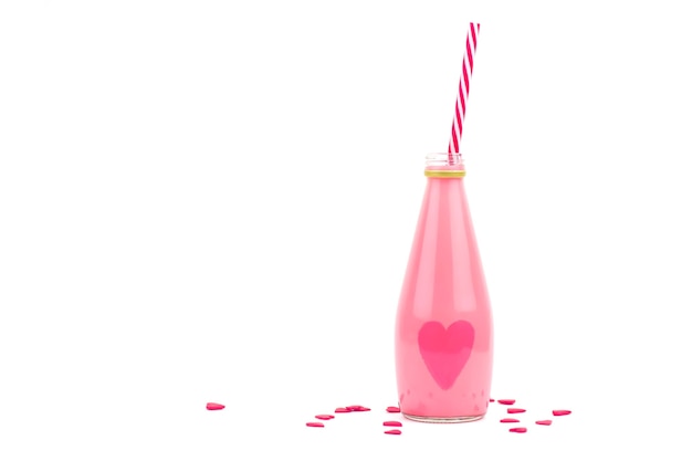 Kleine glazen fles met roze milkshake en rode harten