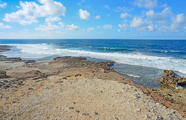 Kleine golven en bruine rotsen in Argentiera Sardinië