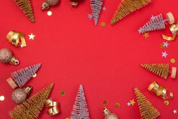 Kleine gouden en zilveren kerstboom gouden kerstballen gouden confetti op rode achtergrond